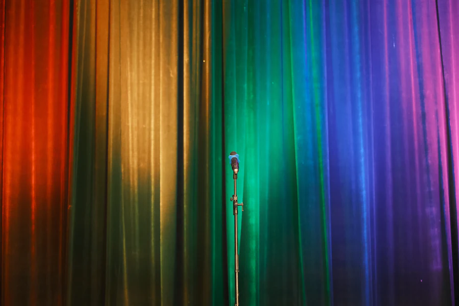 Microphone stand in front of a rainbow-lit curtain